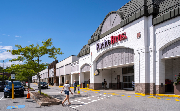 Patrons approaching Roche Bros. supermarket in busy parking lot.