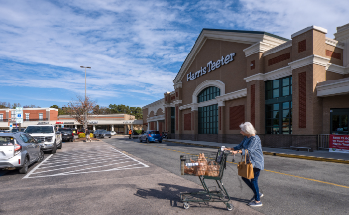 Woman pushing shopping cart in front of Harris Teeter.