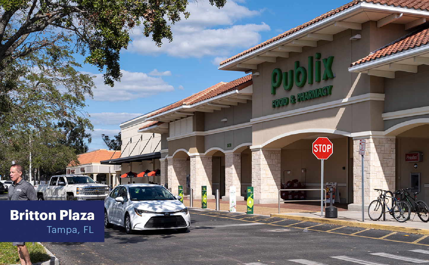 Line of cars passing Publix supermarket on road in front.