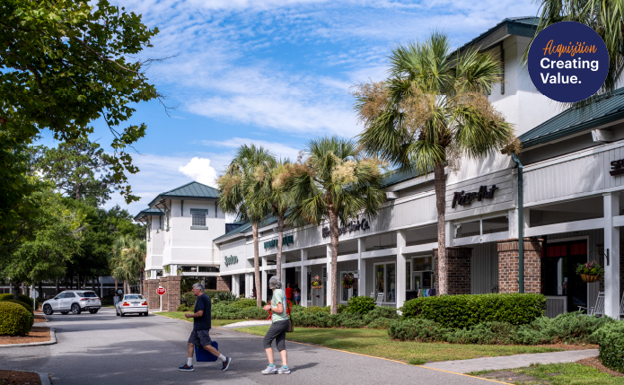 Man and woman walking on road in front of palm trees and Pizza Hut storefront.