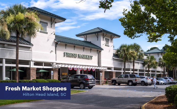 Fresh Market storefront with busy parking lot, palm trees and access road.