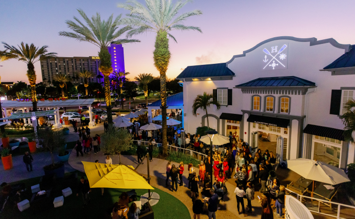 Busy courtyard at Pointe Orlando with umbrellas, seating and palm trees.