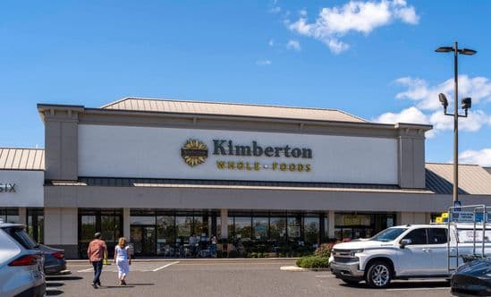 Two patrons approach Kimberton Whole Foods through parking lot.