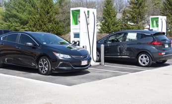 Two electric cars charging at an EV charging station in the parking lot