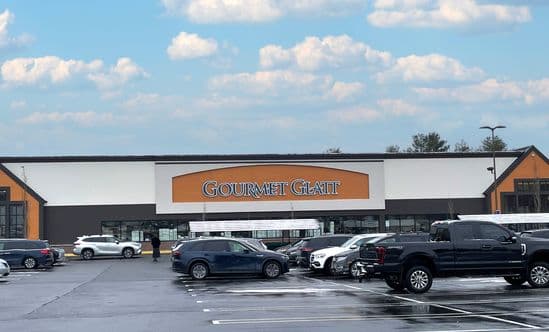 Gourmet Glatt storefront and parking lot with blue sky above.