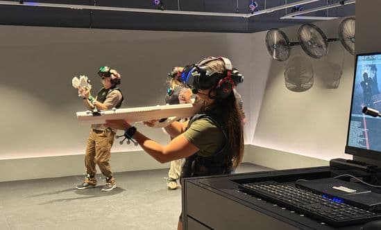 three people wearing VR headsets with VR guns playing in Sand Box at Pointe Orlando