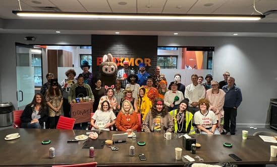large group of people in a conference room wearing halloween costumes