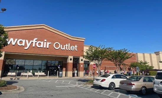 Exterior view of Wayfair outlet between rows of cars leading up to store entrance