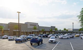 Updated grocery‑anchored retail building at Sunrise Town Center in Sunrise, FL, shown with stone accent columns, wide sidewalks, palm‑lined frontage, and customer vehicles filling the surrounding parking area.