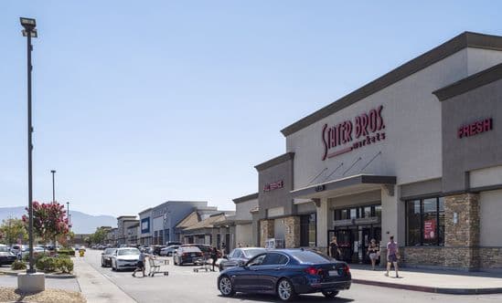 Shoppers and cars on busy road in front of Stater Bros. Market