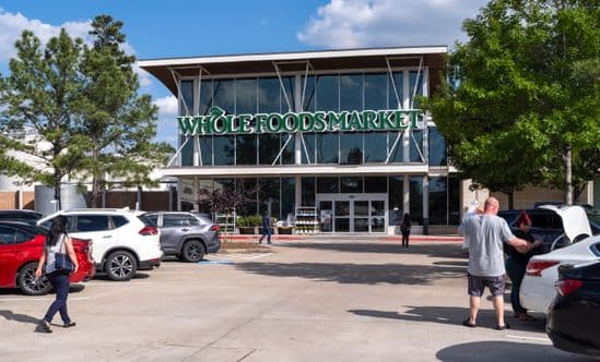 Shoppers in tree-lined parking lot of Whole Foods Market
