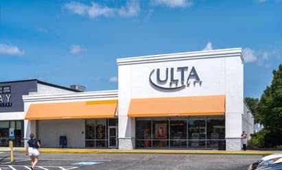 Ulta Beauty at Watertower Plaza in Leominster, MA, featuring a bright white façade with orange awnings, large storefront windows, accessible parking spaces, and a paved drive aisle under a sunny blue sky.