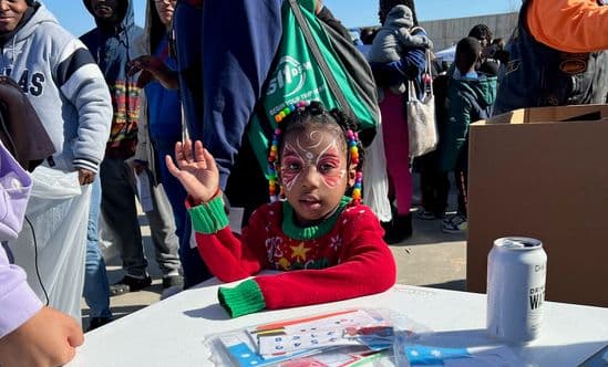 young girl with butterfly face paint sitting at a table