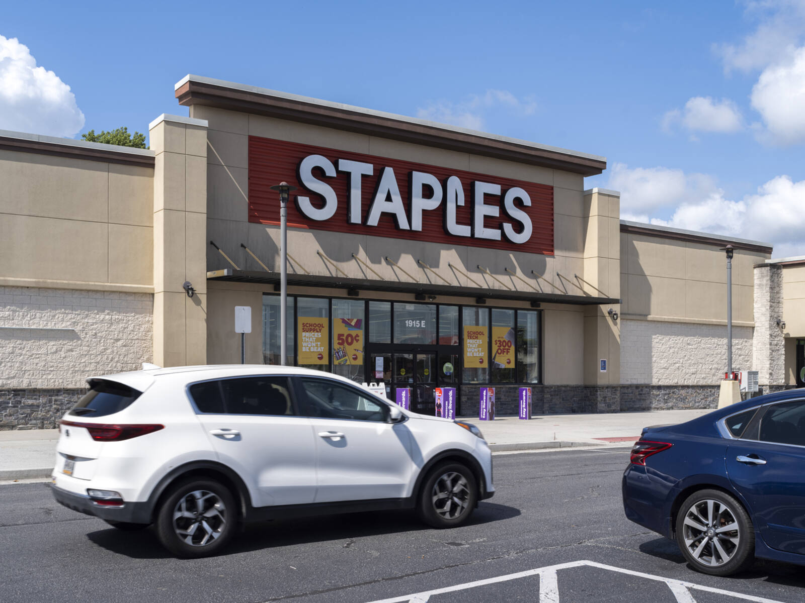 White SUV in front of Staples storefront at Victory Square.