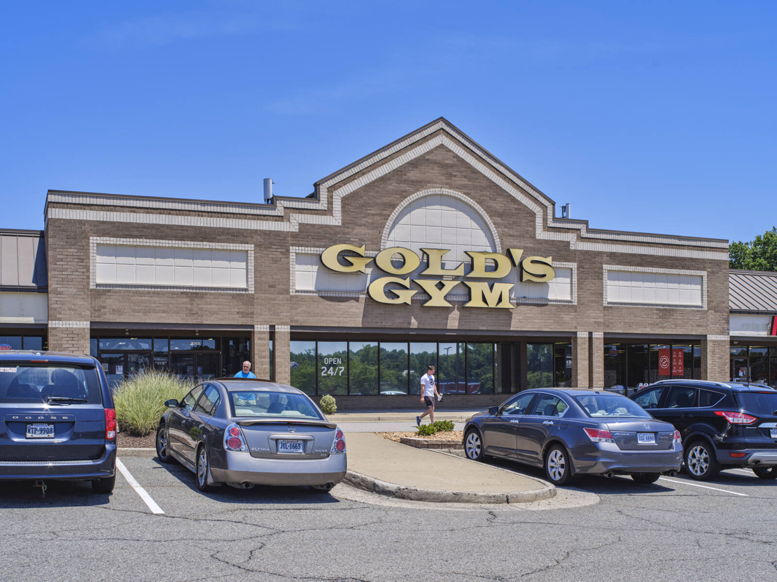 Two men exit Gold's Gym into the parking lot at Hanover Square.