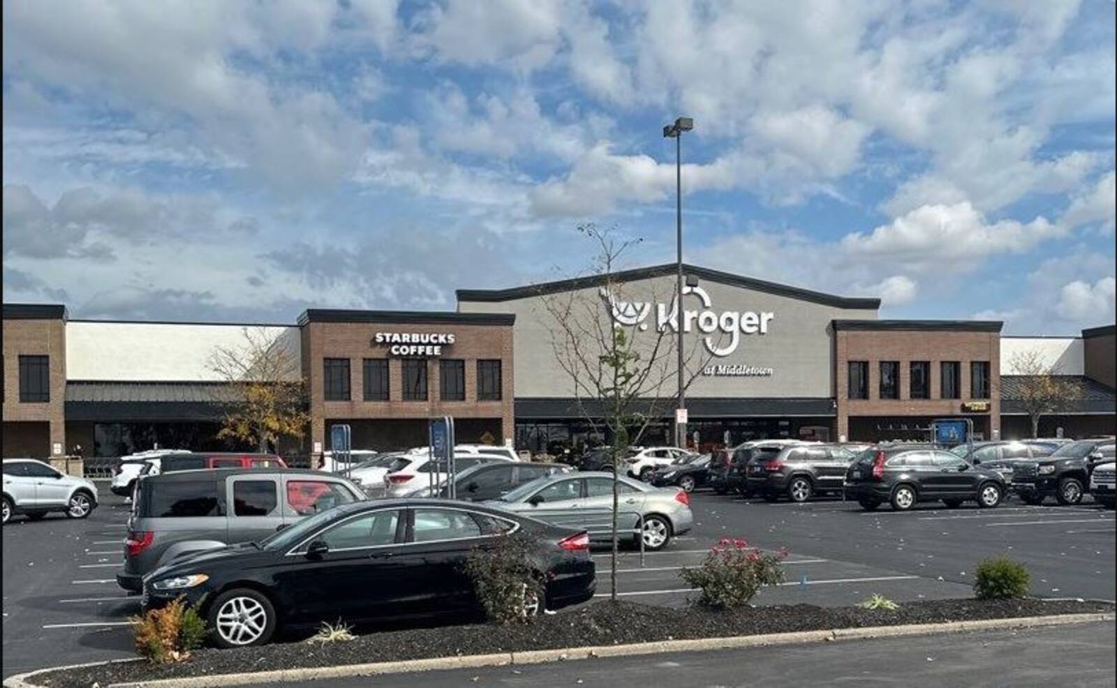 Parking lot and Kroger in background with cloudy blue sky above.