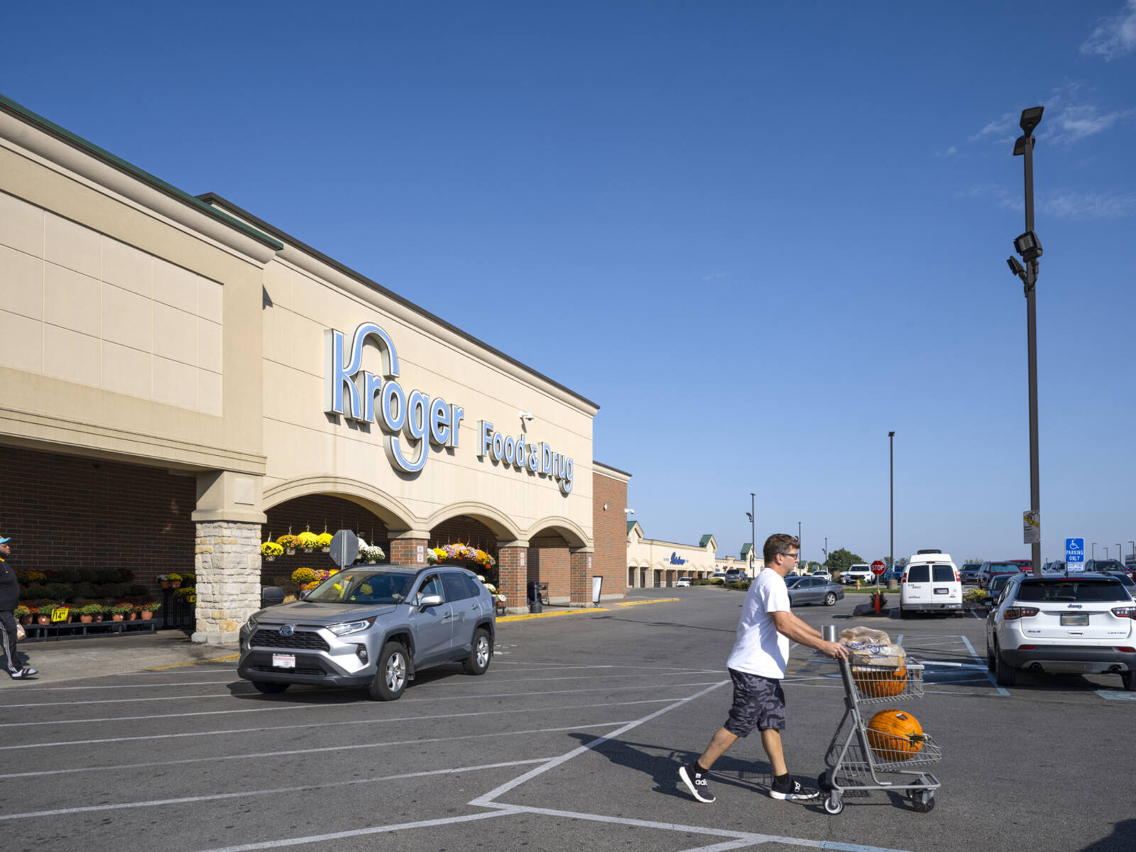 Man with carriage walking towards parking lot at Kroger.