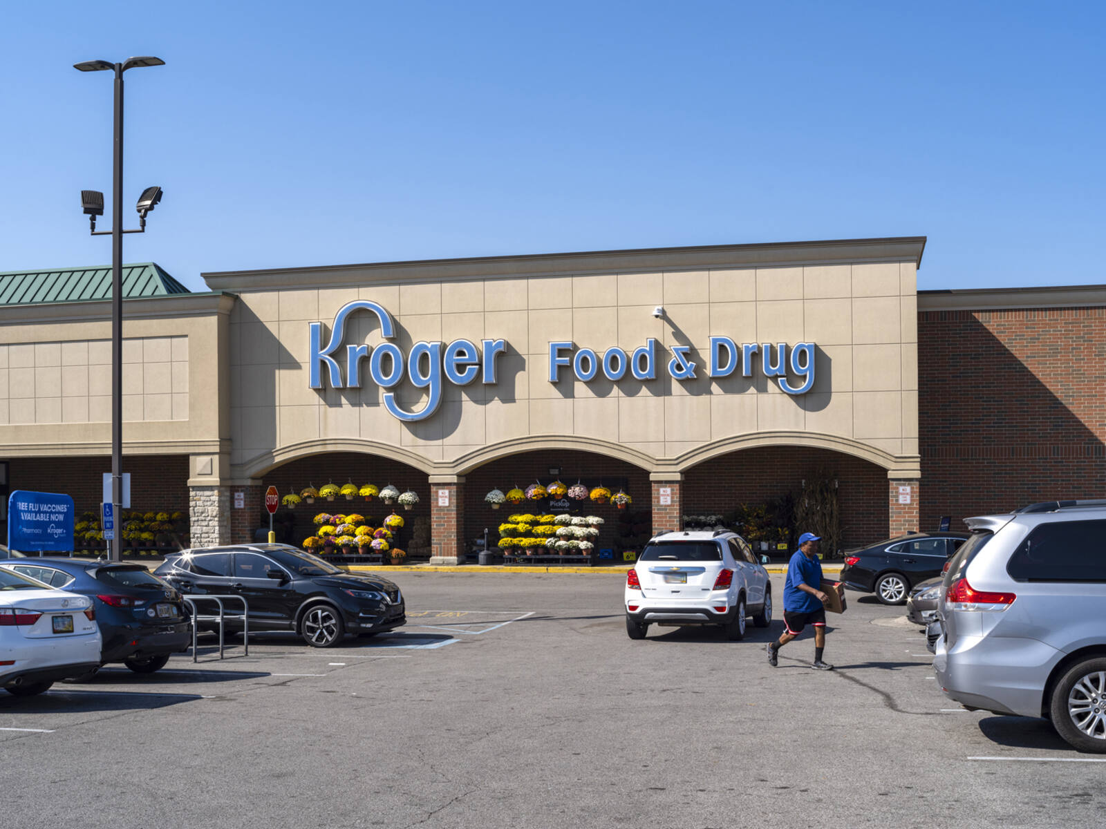 Man and white SUV in parking lot aisle in front of Kroger.
