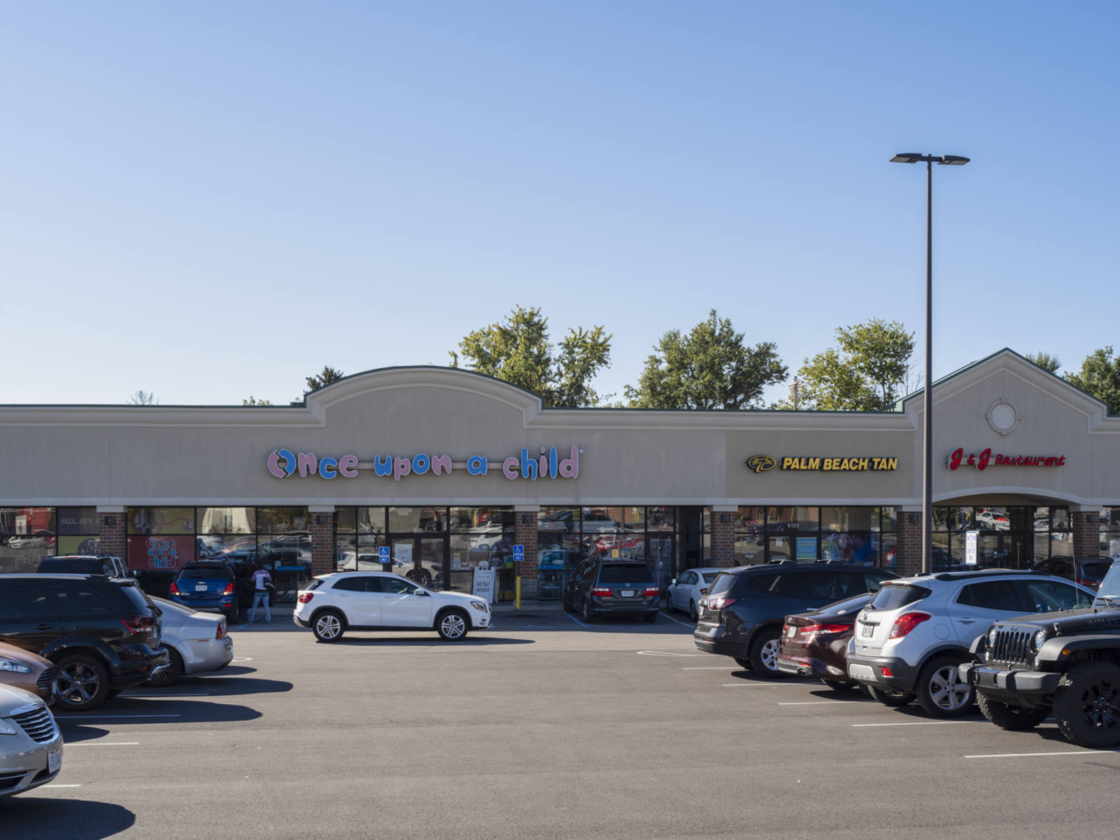 White SUV driving in front Once-upon-a-child with a full parking lot