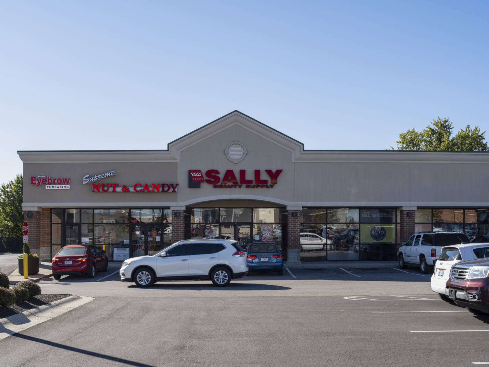 White SUV passing by the entrance of Sally at Western Village Shopping Center