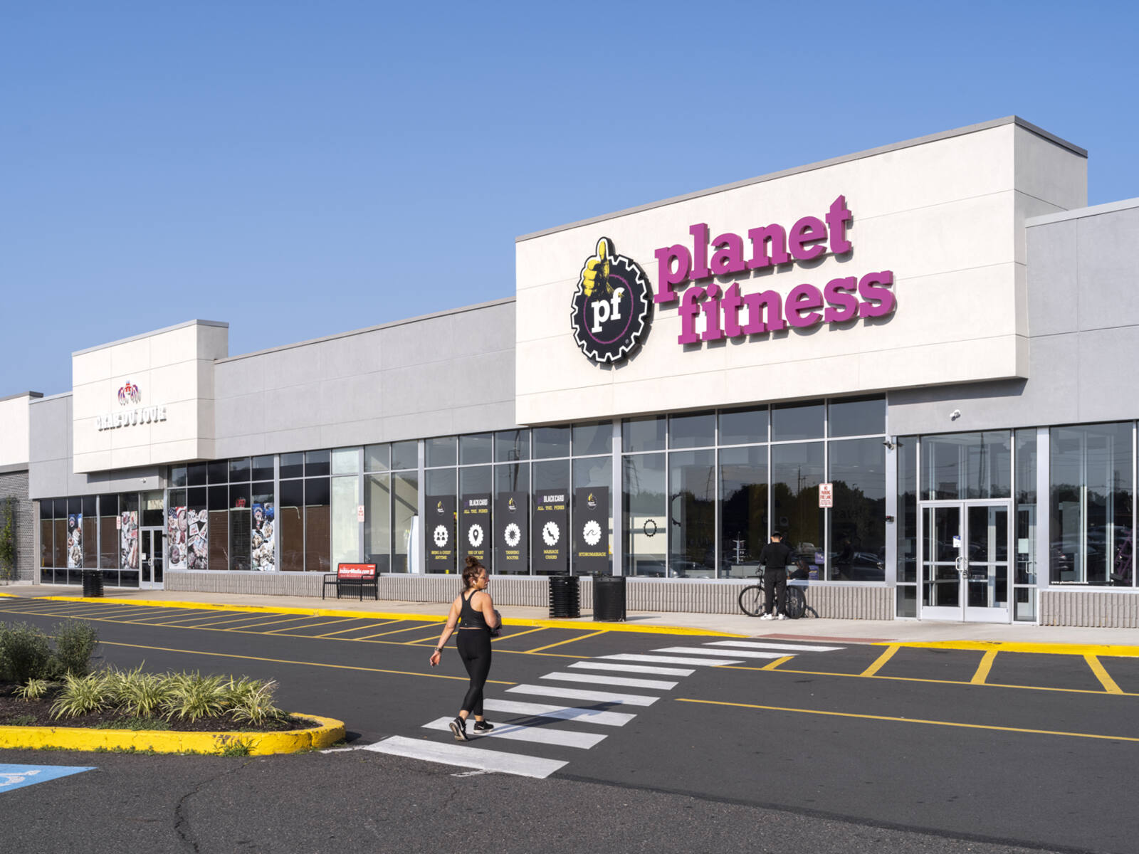 Woman in crosswalk walking towards Planet Fitness.