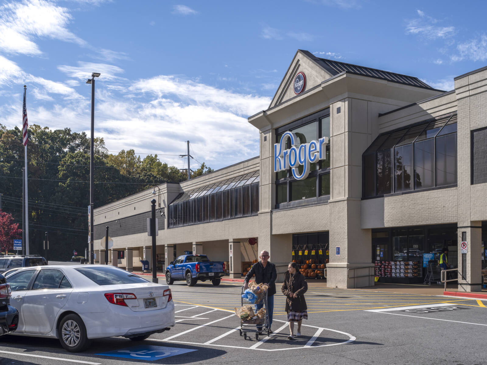 Man and woman leaving Kroger with full shopping cart into the parking lot.