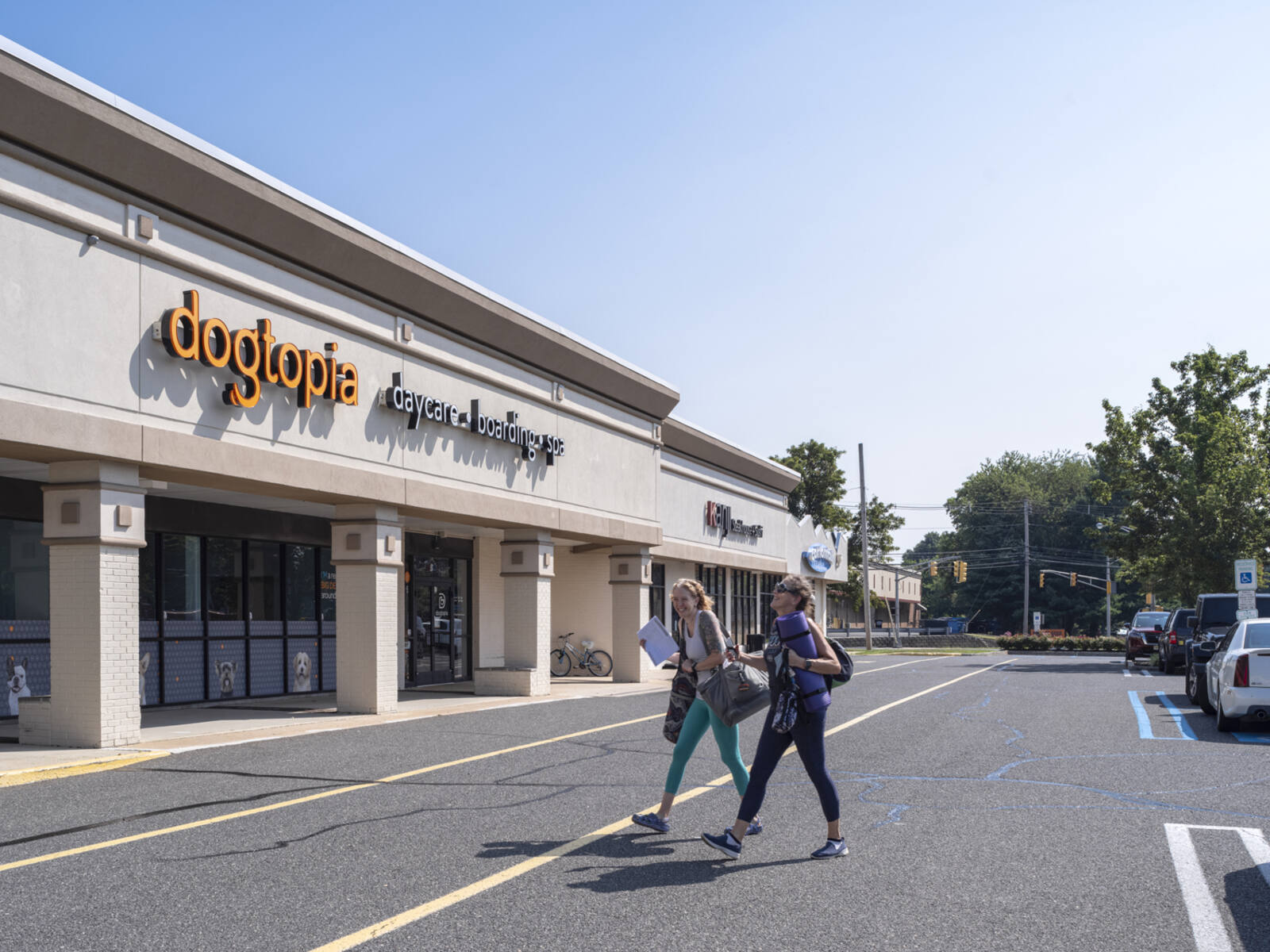 Two women walking on road in front of Dogtopia salon.
