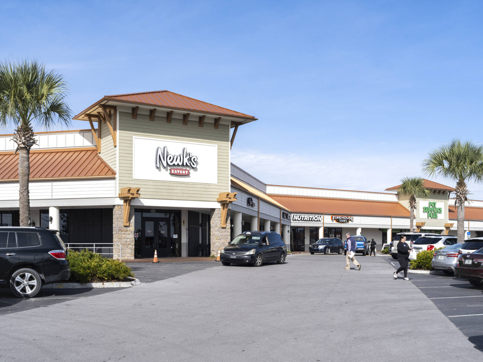 Busy parking lot in front of Newk's Eatery with cars and patrons on access road in front.