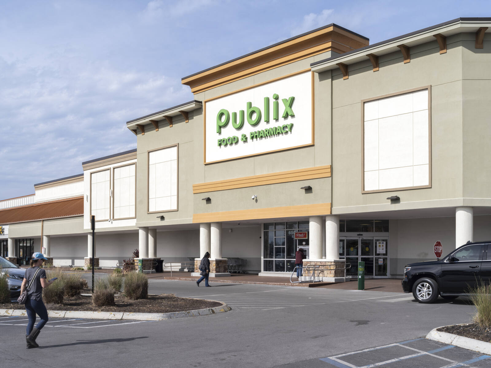 Man walks towards Publix entrance through parking lot.