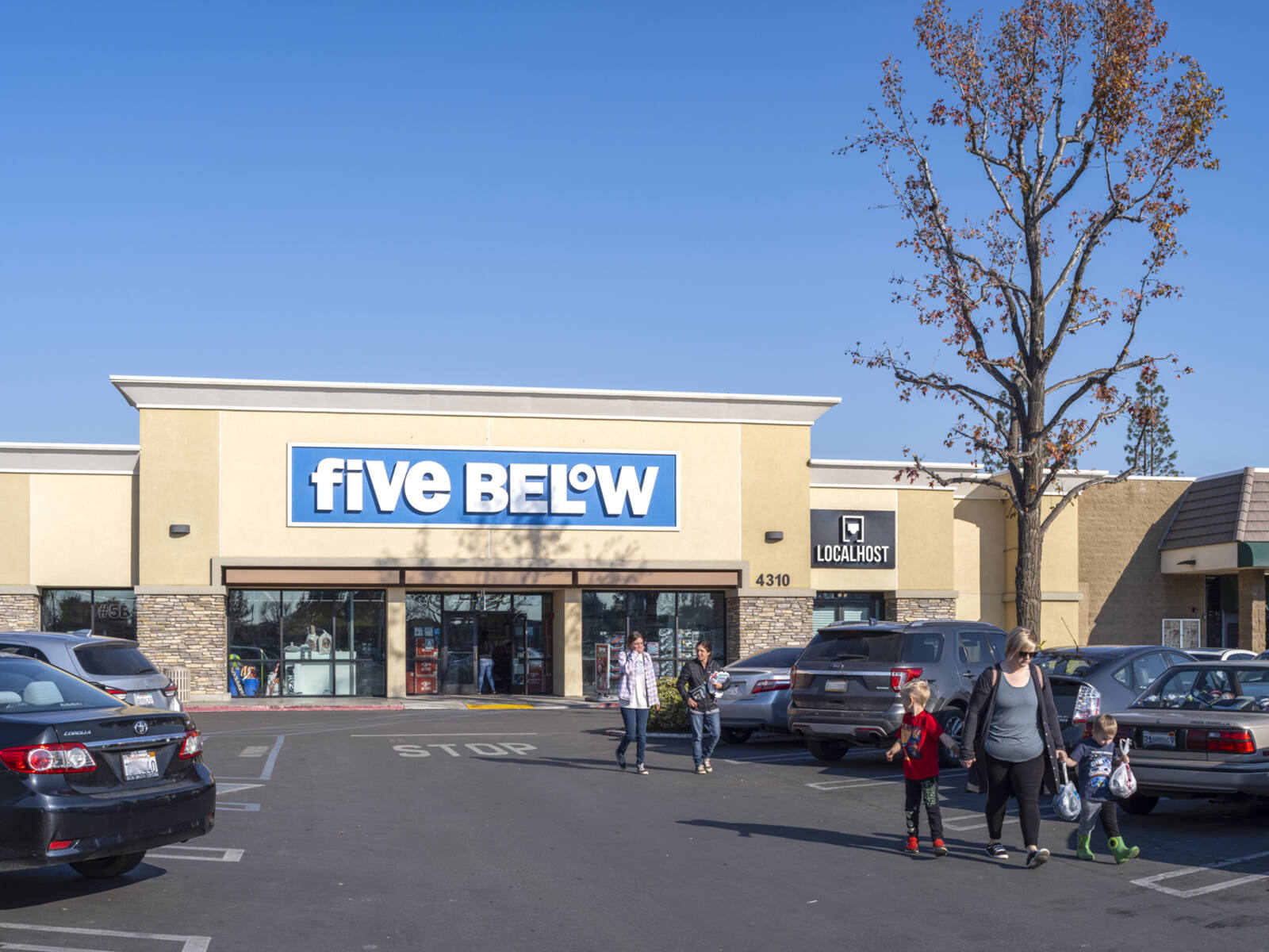 Pedestrians with children exiting Five Below into the parking lot.