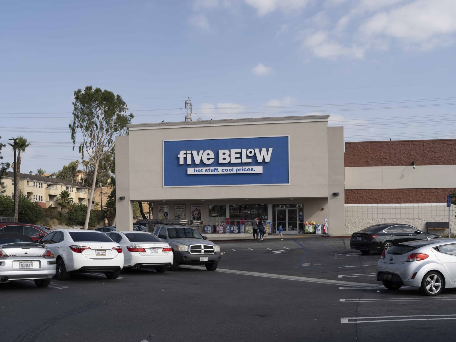 Family enters Five Below amongst row of parked cars in Montebello, CA.