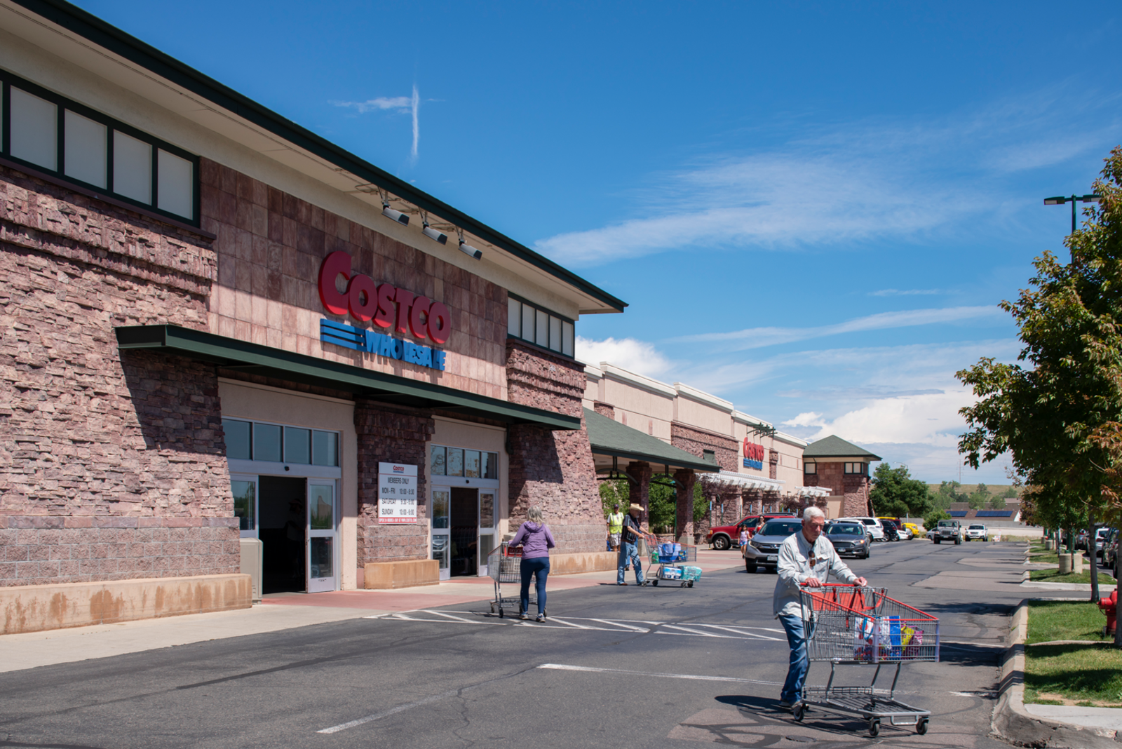 Person with shopping cart walking away from Costco entrance