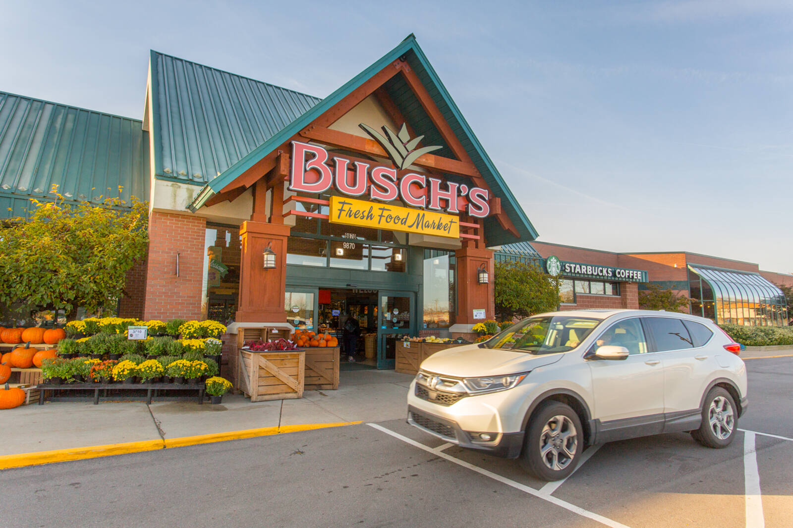Grey SUV, pumpkins and small plants at the front of Busch's market at Grand Crossing.