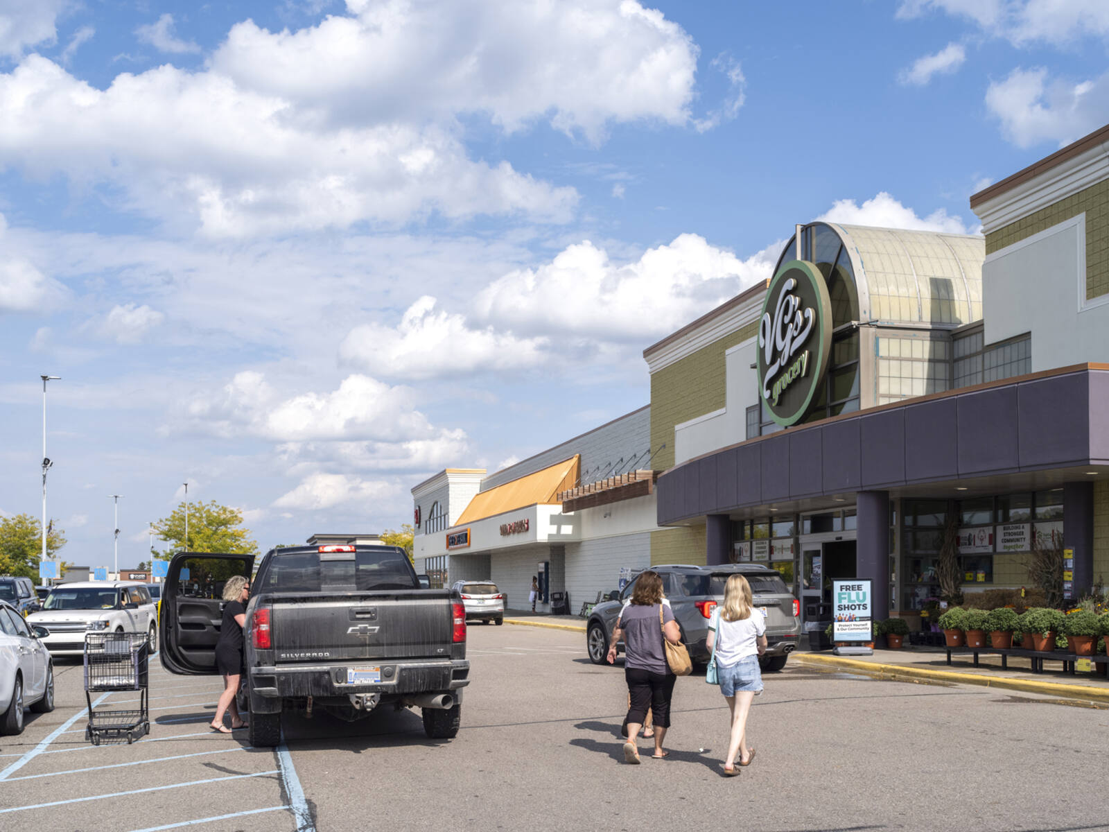 Busy crosswalk with pedestrians and truck at VG's Grocery.