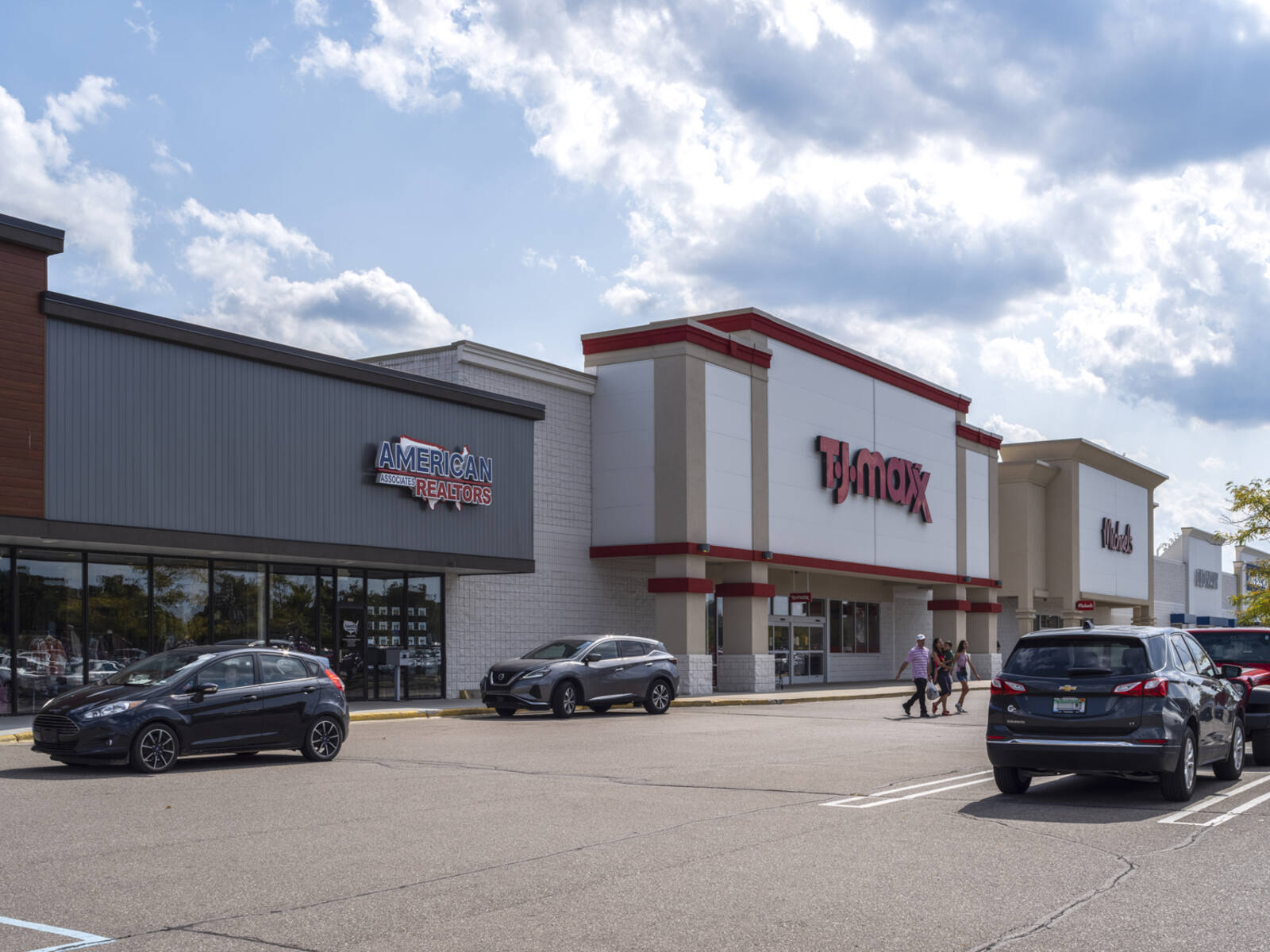Customers exit TJ Maxx into parking lot.