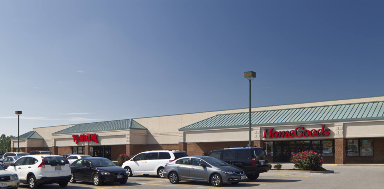 T.J. Maxx, HomeGoods with parking lot in front and clear blue sky.