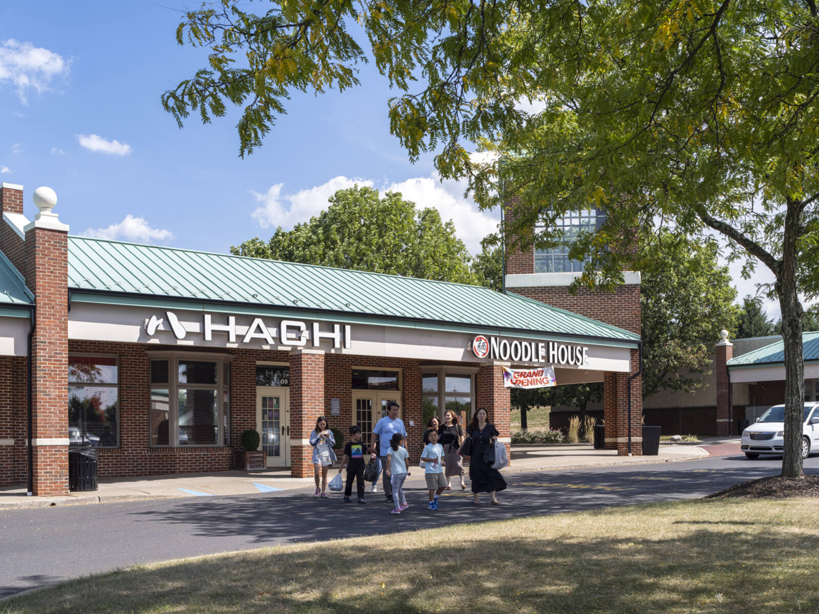 Family exiting Hachi restaurant into the shade of a tree.