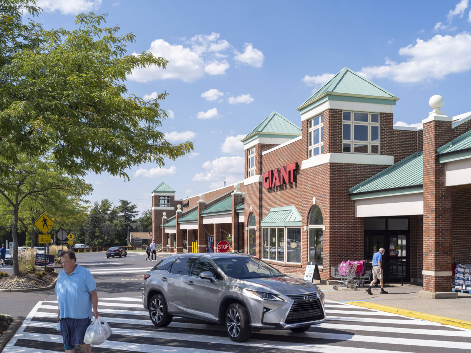 Pedestrian with bag and car in front of Giant grocer.