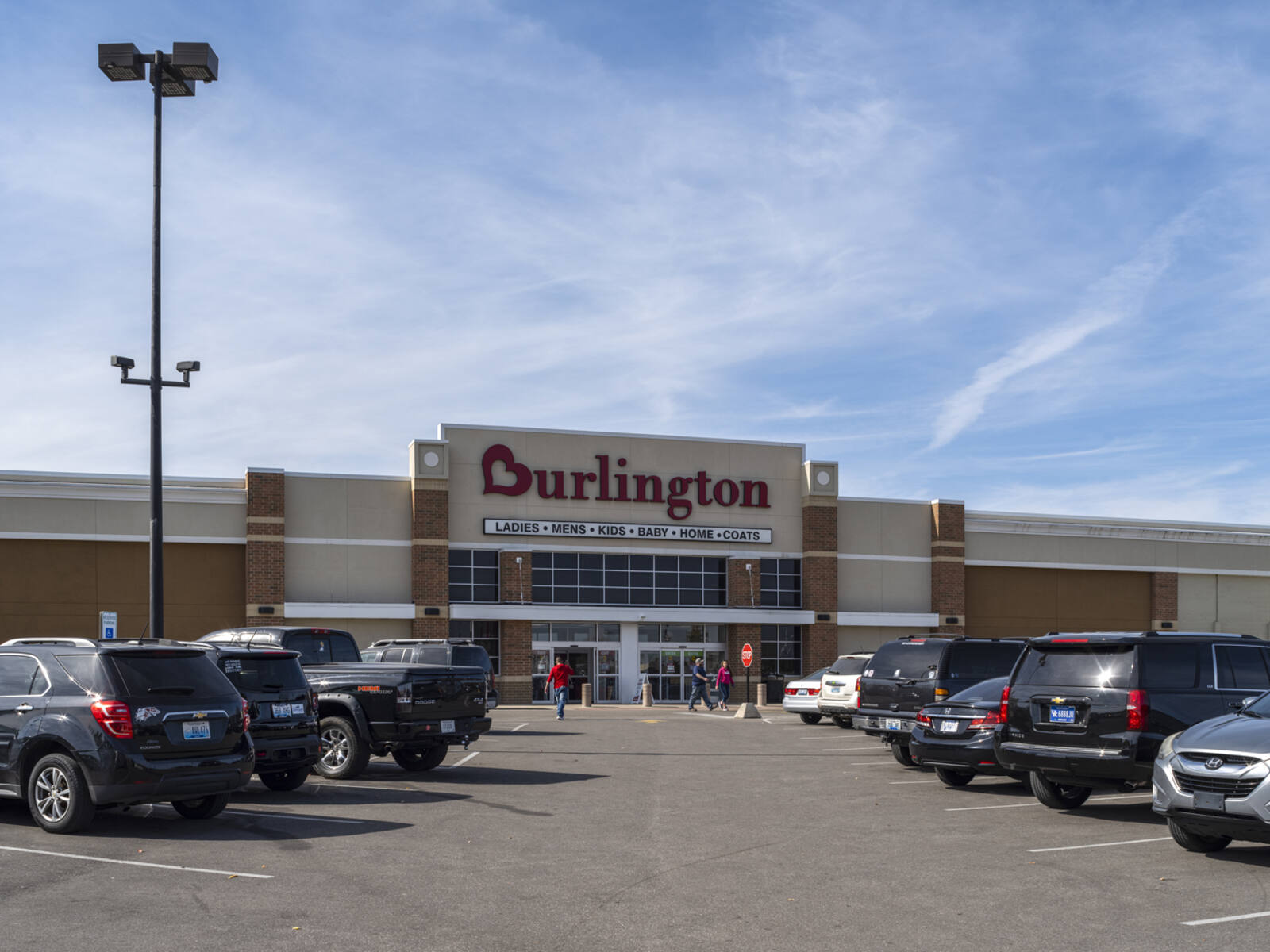 Customers exit Burlington into a busy parking lot.