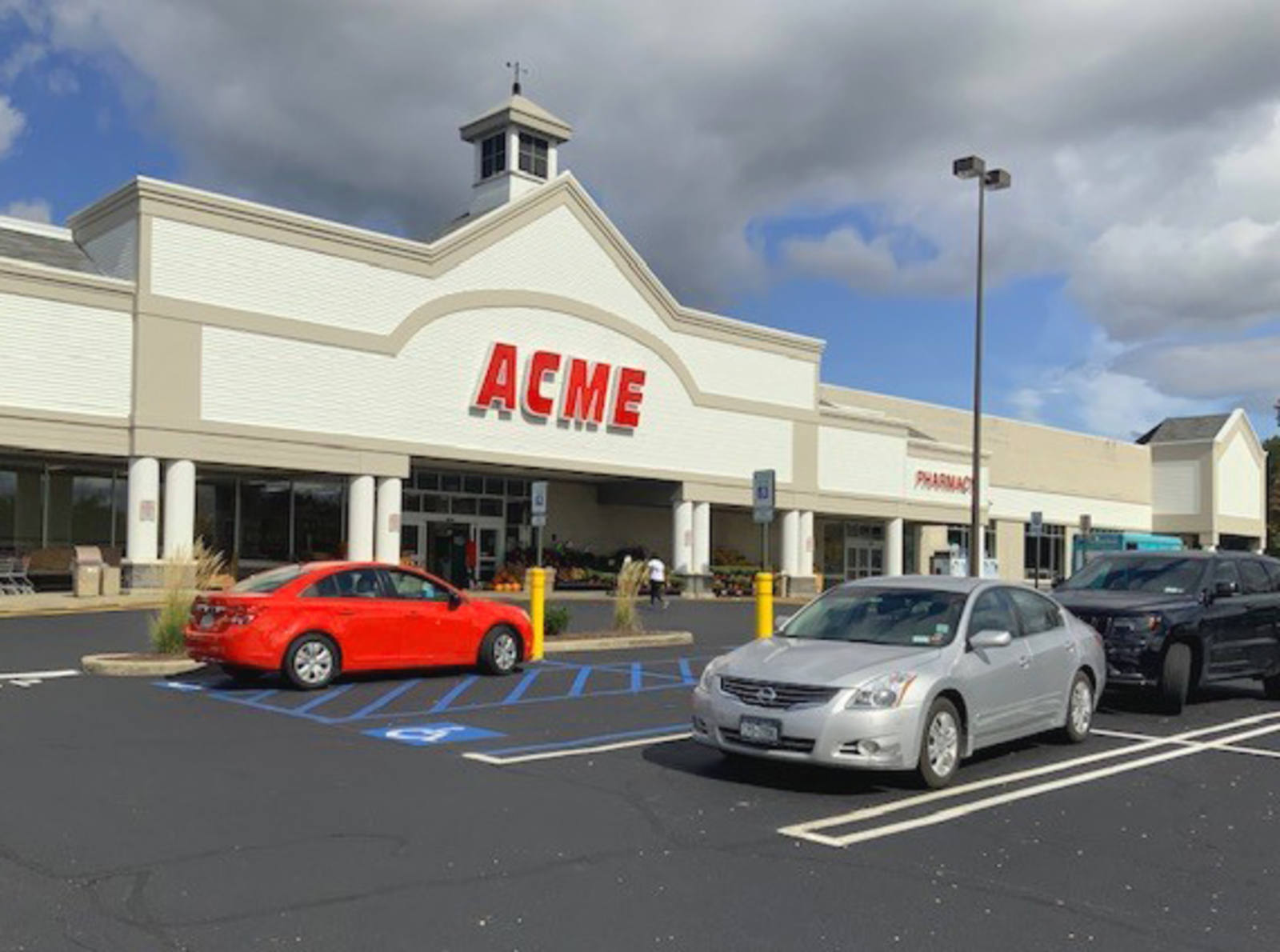 Red car and silver car in parking lot of Acme at Unity Plaza Shopping Center