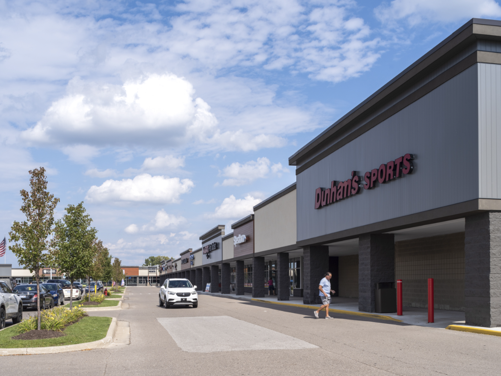 Customer approaches Dunham's Sports with white car in background.