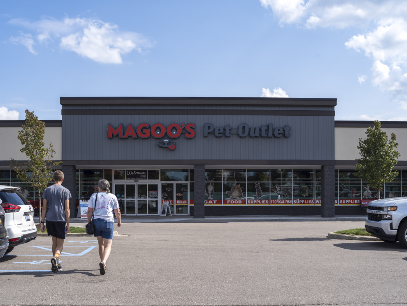 Two pedestrians approach Magoo's Pet-Outlet via the parking lot.