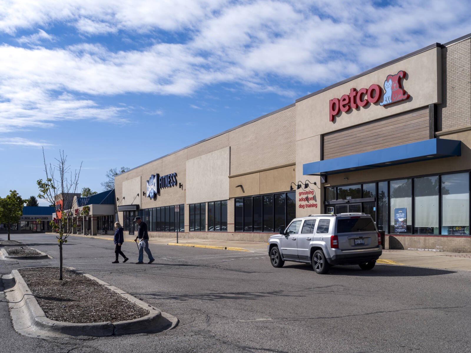 Two customers leaving petco store into parking lot.