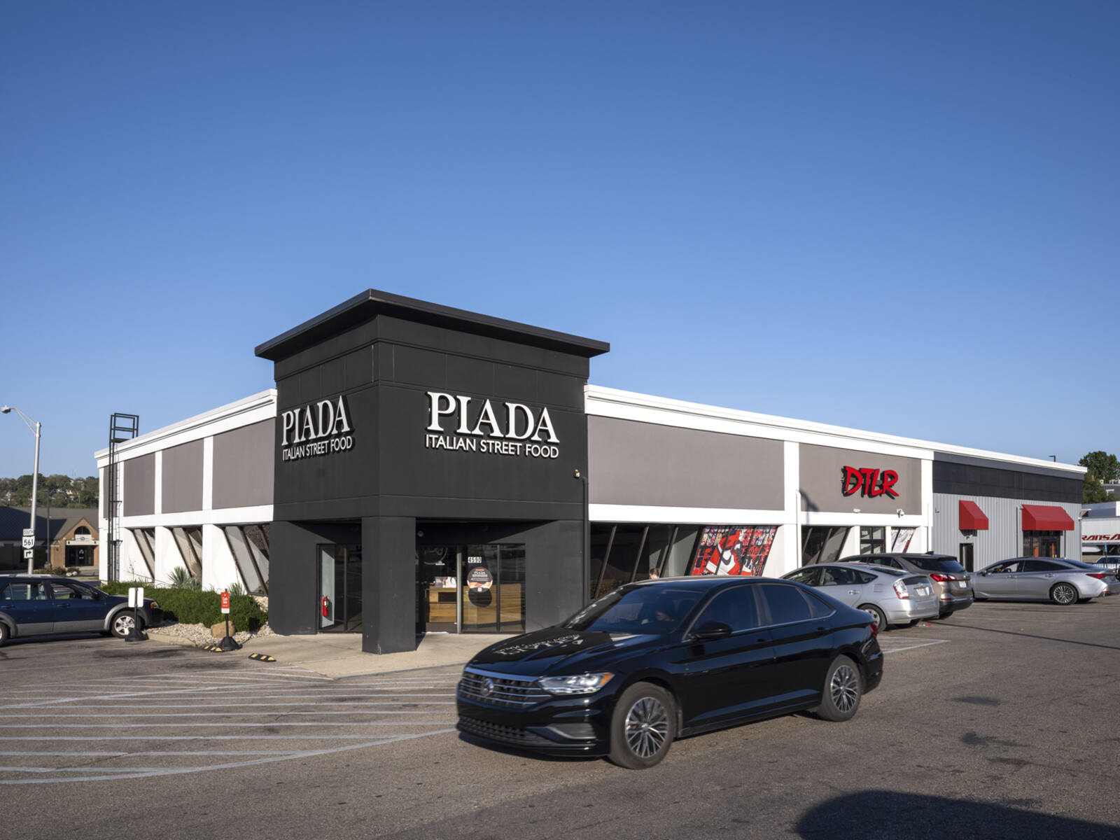 Dark car in front of Piada Italian Street Food in parking lot.