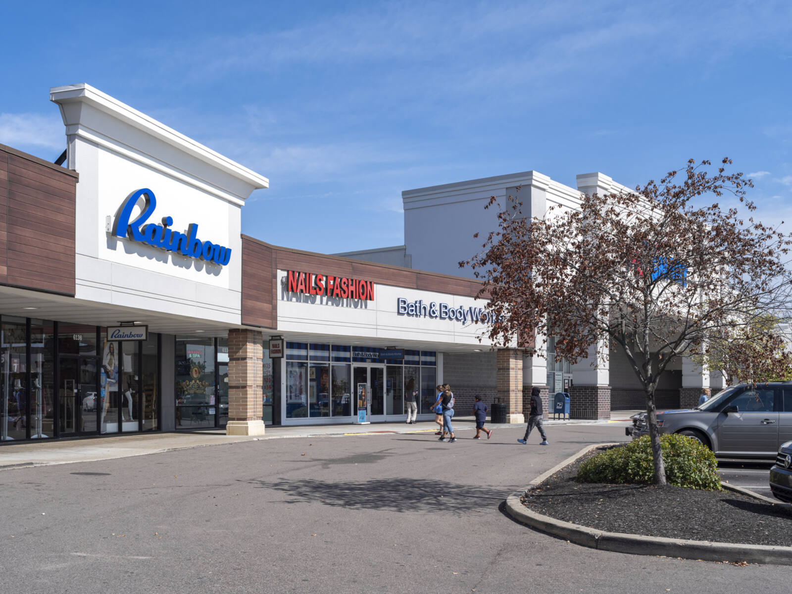 3 pedestrians cross road to enter Rainbow department store.