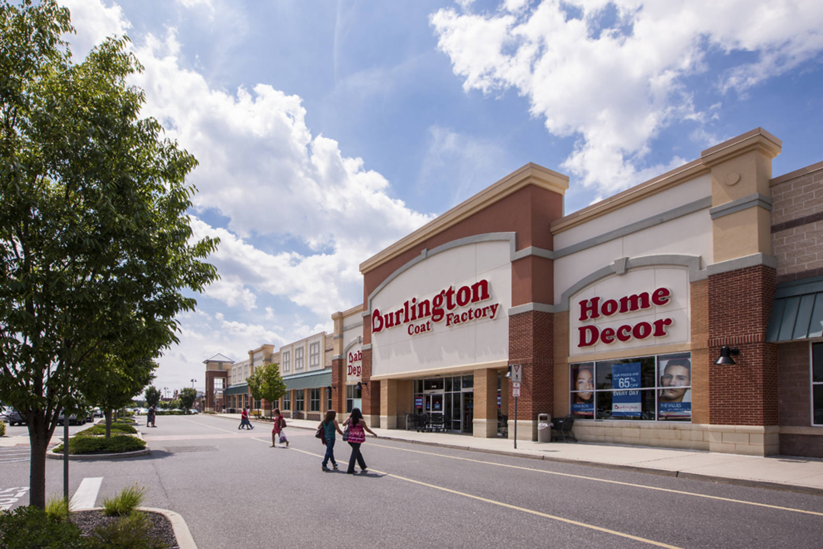 People walking into entrance of Burlington with a tree on the left
