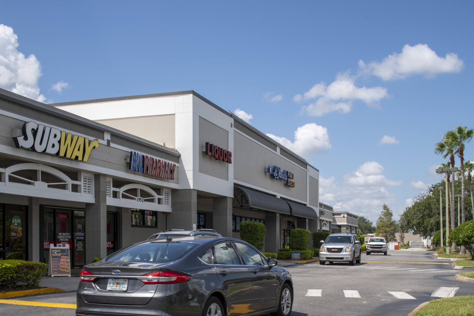 Dark grey car driving past Subway at Ventura Downs shopping center