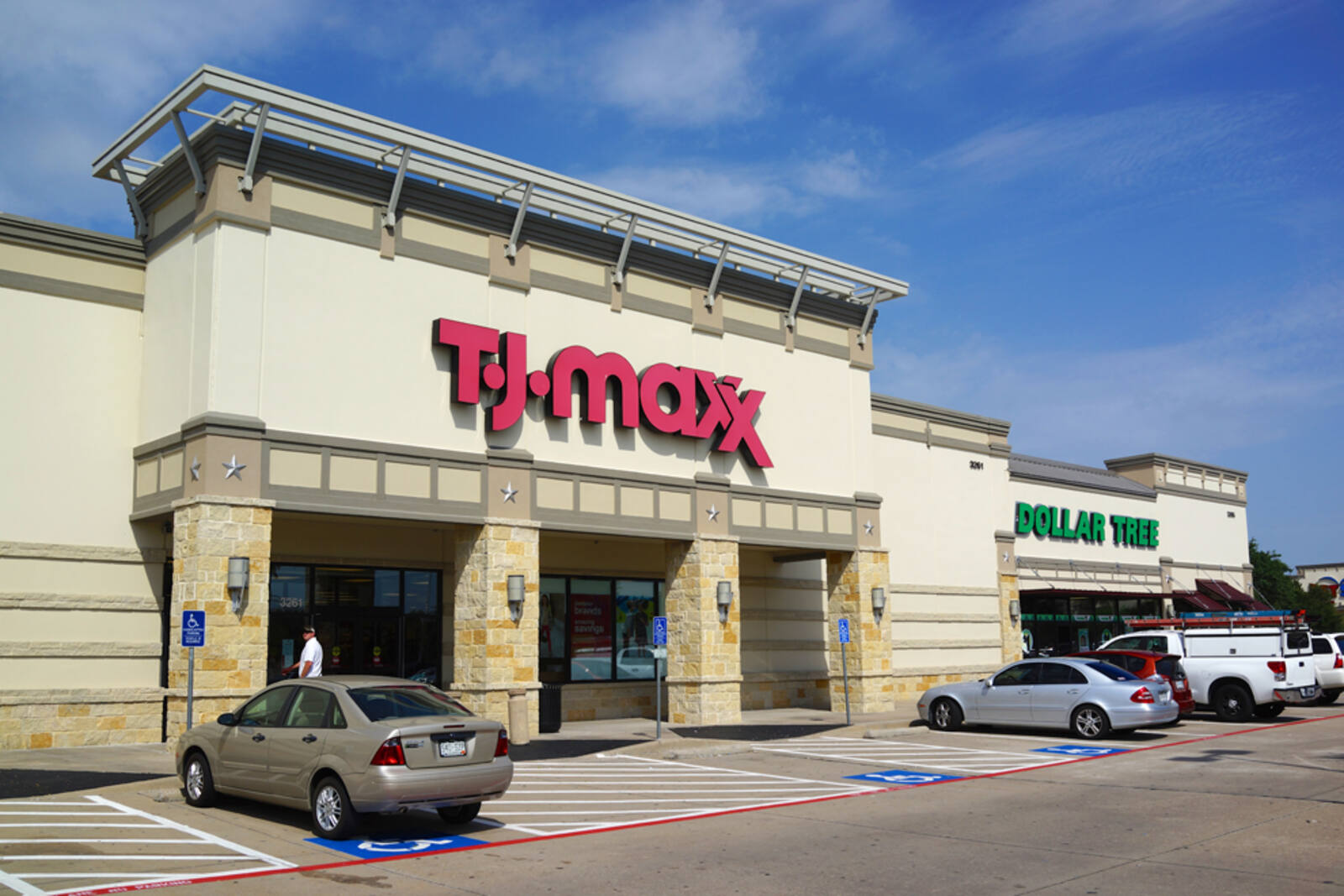 Cars sporadically parked outside of T.J. Maxx and  Dollar Tree on a sunny day