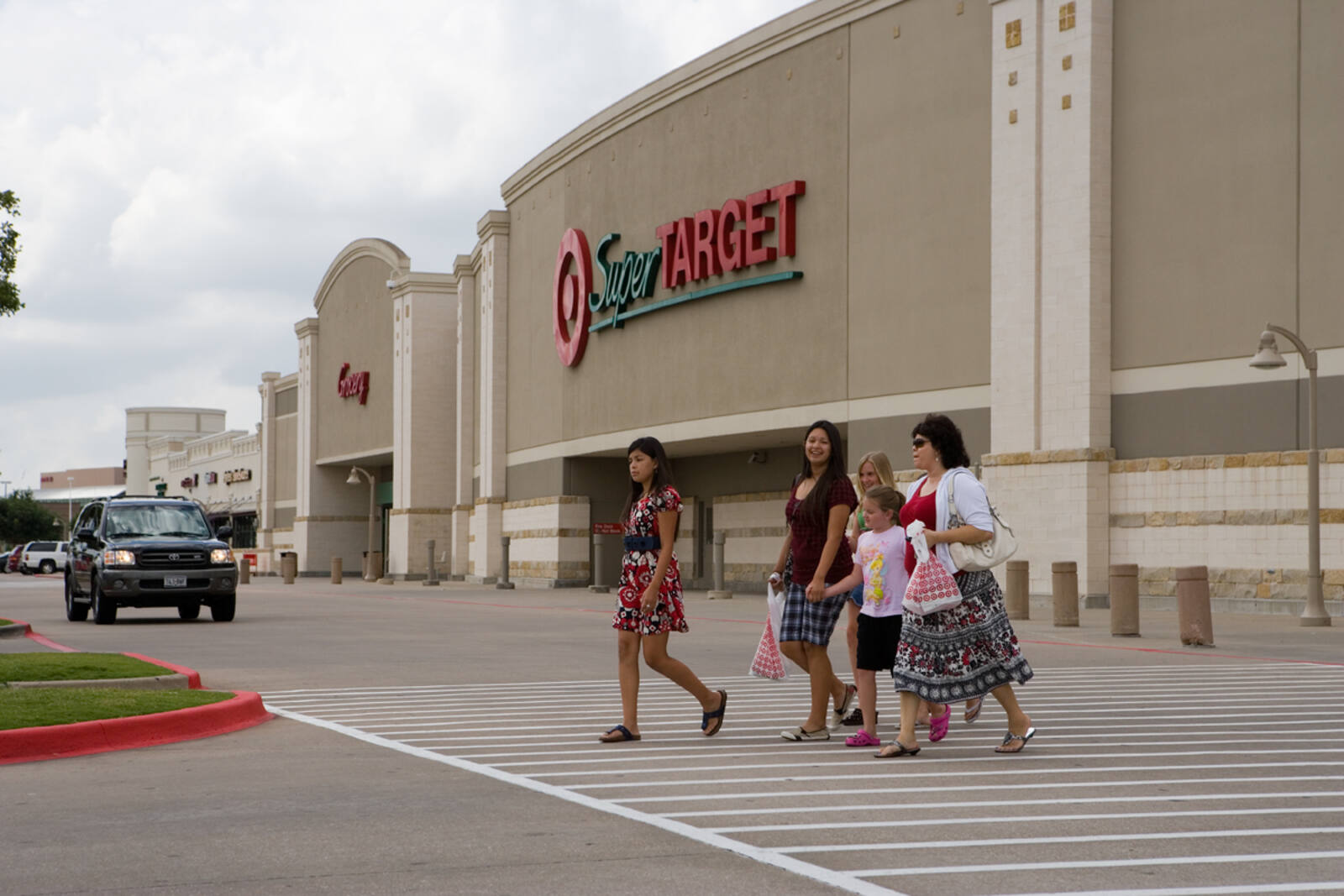 Black SUV and group of four people in front of entrance to Super Target