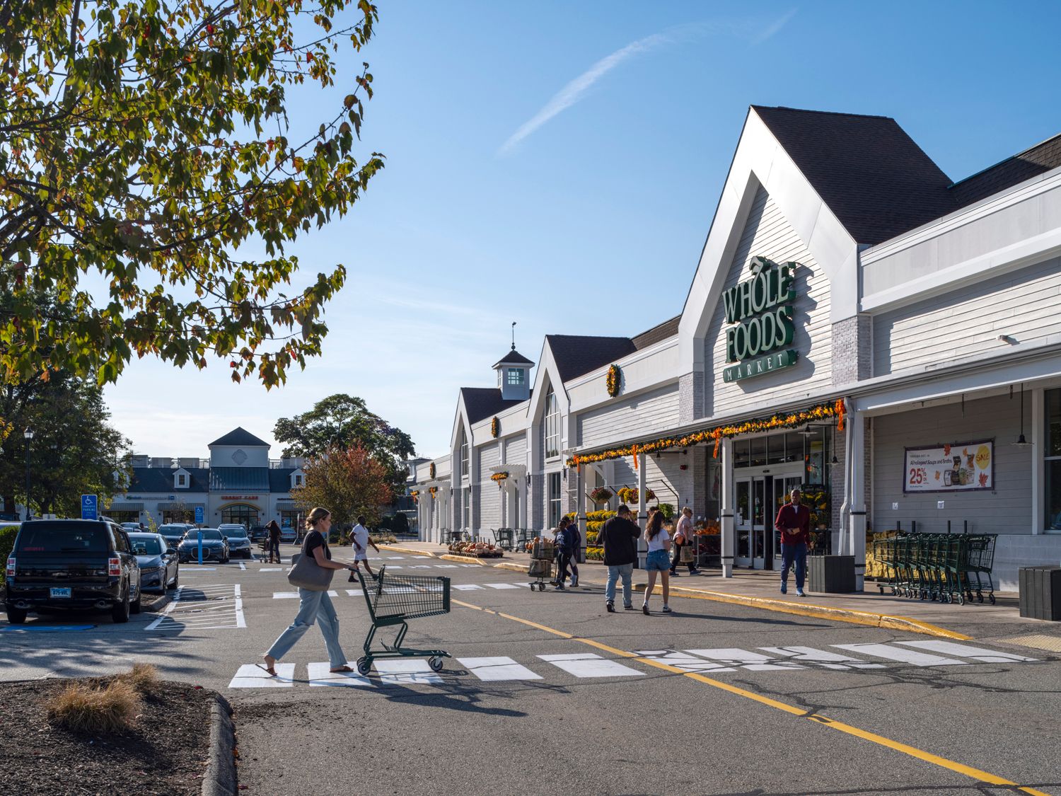 Shoppers with carts in crosswalk of Whole Foods Market.